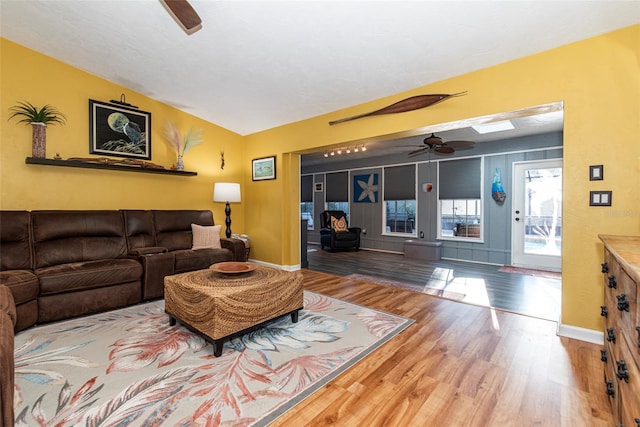 living room with wood-type flooring, a skylight, and ceiling fan