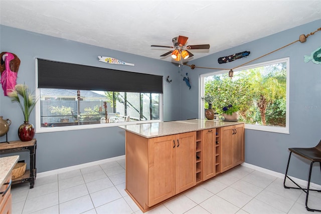 kitchen featuring ceiling fan, light tile patterned flooring, light stone counters, and kitchen peninsula