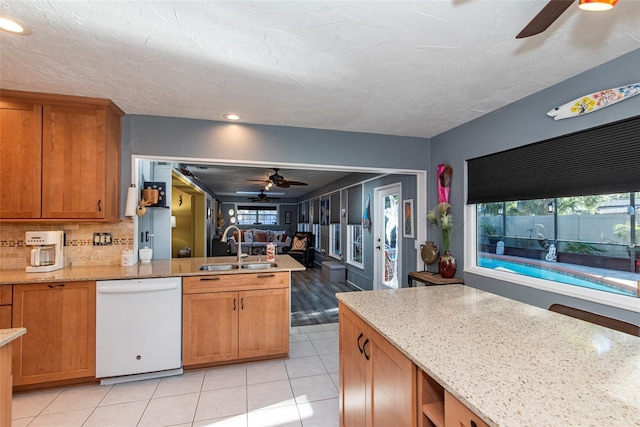 kitchen featuring light stone countertops, dishwasher, light tile patterned floors, and sink