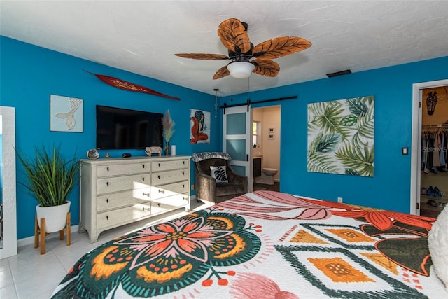 bedroom with a walk in closet, a textured ceiling, ceiling fan, connected bathroom, and a closet