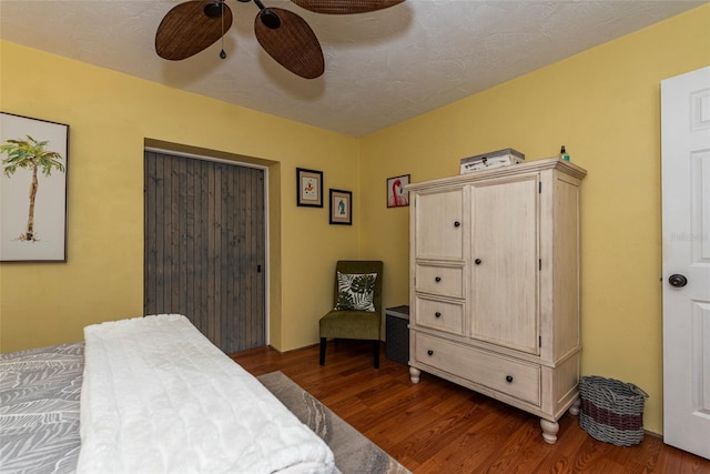 bedroom with a textured ceiling, ceiling fan, and dark wood-type flooring