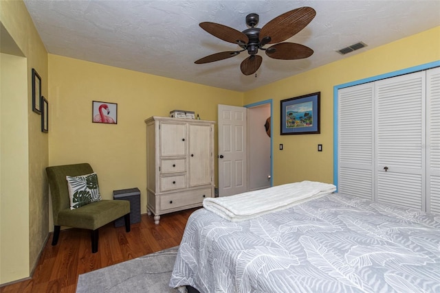 bedroom with a textured ceiling, dark hardwood / wood-style flooring, a closet, and ceiling fan