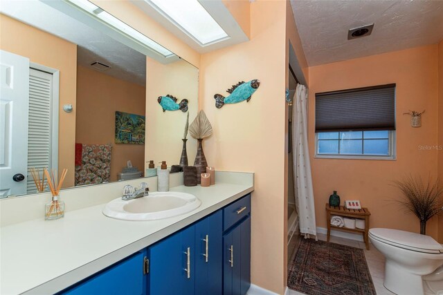 full bathroom with tile patterned floors, vanity, a textured ceiling, shower / tub combo with curtain, and toilet