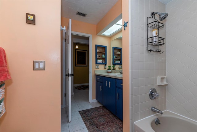 bathroom with tile patterned flooring, vanity, and tiled shower / bath