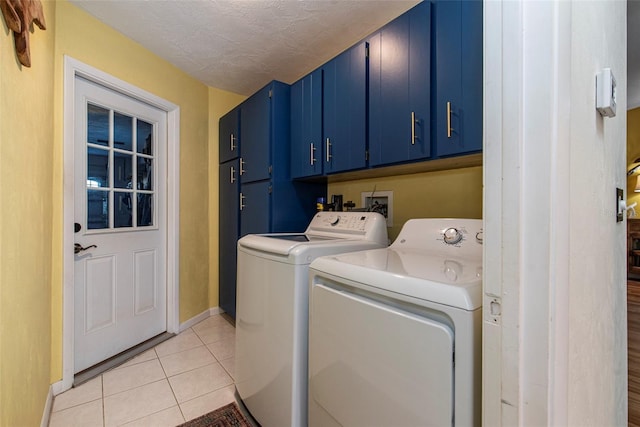 washroom with cabinets, independent washer and dryer, a textured ceiling, and light tile patterned floors