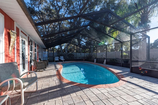 view of pool with glass enclosure and a patio