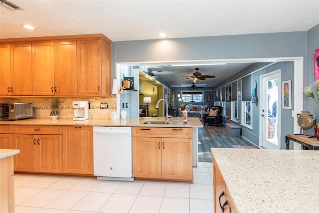 kitchen featuring dishwasher, ceiling fan, light stone countertops, and sink