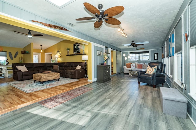 living room featuring lofted ceiling, a textured ceiling, and hardwood / wood-style flooring