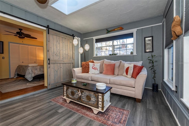 living room with dark hardwood / wood-style flooring, a barn door, and ceiling fan