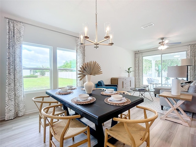 dining space with ceiling fan with notable chandelier, light wood-type flooring, and a healthy amount of sunlight