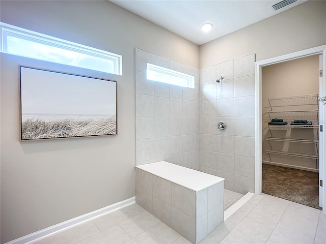 bathroom with tile patterned flooring and a tile shower