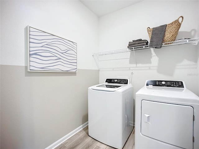 laundry area with washing machine and dryer and light wood-type flooring