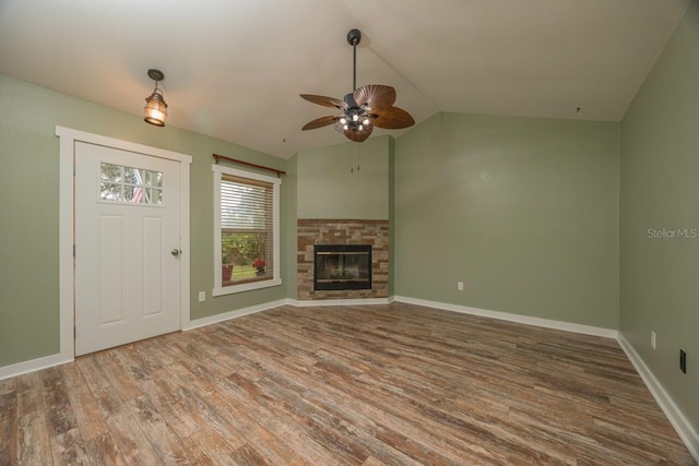 unfurnished living room featuring a stone fireplace, ceiling fan, wood-type flooring, and vaulted ceiling