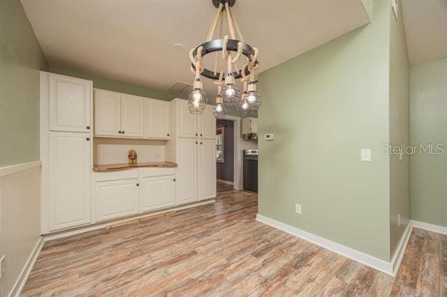 kitchen with a notable chandelier, decorative light fixtures, white cabinetry, and light hardwood / wood-style flooring