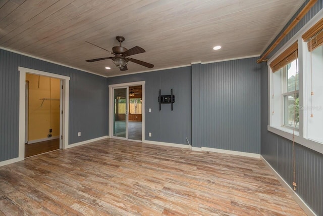 spare room with light wood-type flooring, ornamental molding, wood ceiling, ceiling fan, and wooden walls