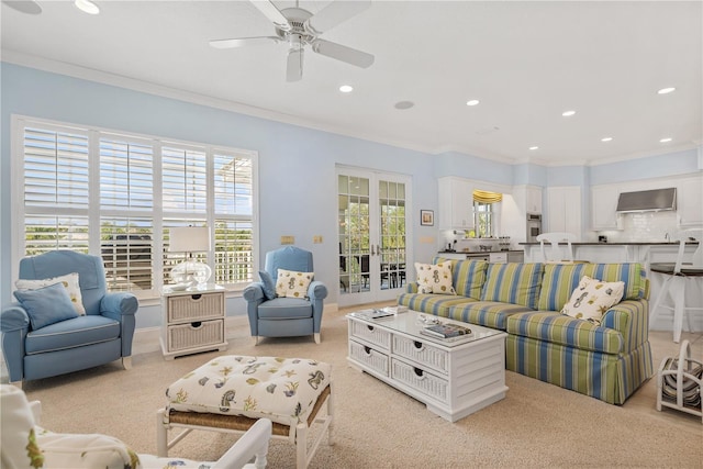 living room featuring ceiling fan, ornamental molding, and light carpet