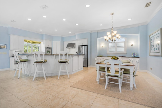 kitchen with appliances with stainless steel finishes, wall chimney exhaust hood, light tile patterned floors, decorative light fixtures, and white cabinets