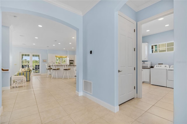 hall with light tile patterned floors, separate washer and dryer, and crown molding