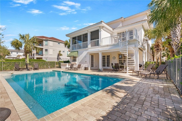 rear view of property with french doors, a patio, a balcony, and a fenced in pool