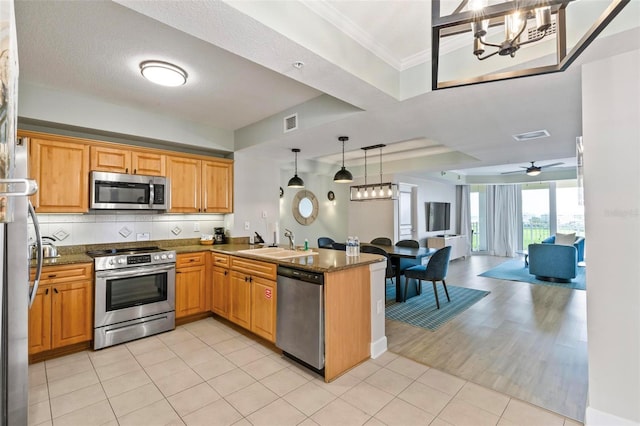 kitchen with sink, stainless steel appliances, kitchen peninsula, ceiling fan with notable chandelier, and light wood-type flooring