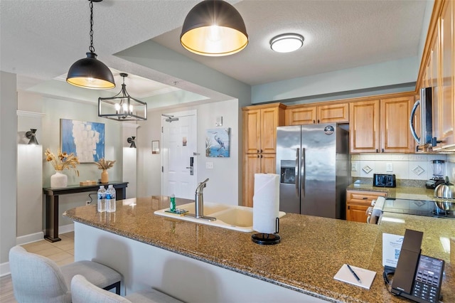 kitchen featuring tasteful backsplash, dark stone countertops, stainless steel appliances, and a textured ceiling