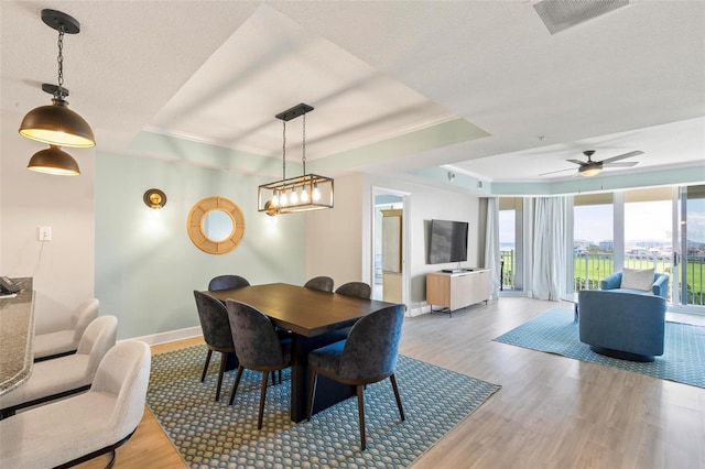 dining room with hardwood / wood-style flooring, crown molding, ceiling fan, and a tray ceiling