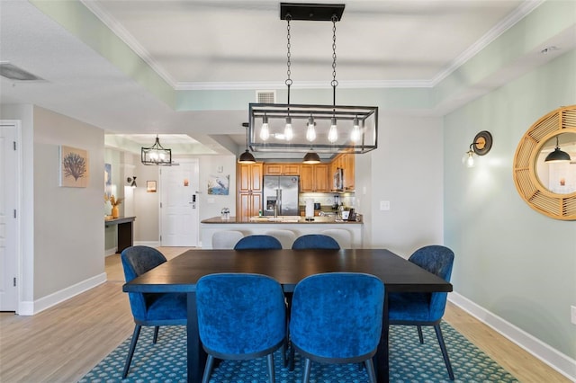 dining area featuring crown molding, light hardwood / wood-style floors, and a notable chandelier