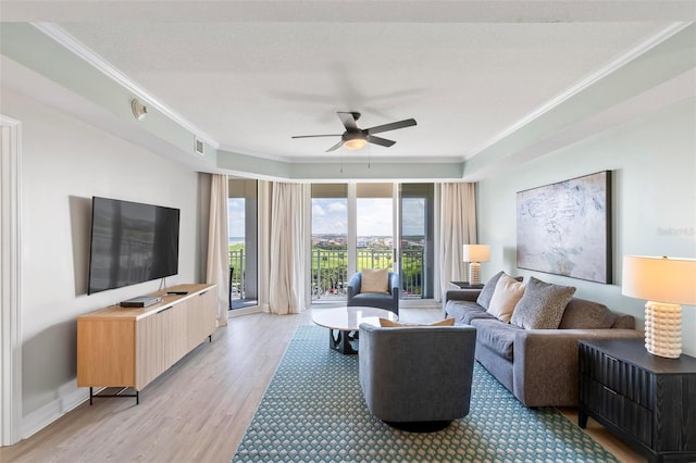 living room featuring ceiling fan, ornamental molding, a textured ceiling, and light hardwood / wood-style flooring