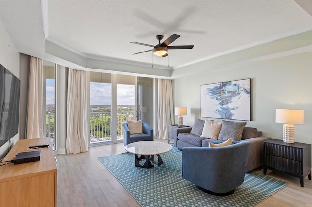 living room featuring crown molding, ceiling fan, light hardwood / wood-style floors, and a textured ceiling