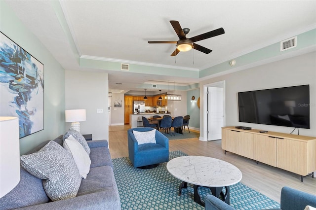 living room with ceiling fan, crown molding, and light hardwood / wood-style flooring