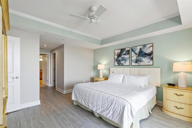 bedroom with a raised ceiling, ceiling fan, light hardwood / wood-style flooring, and crown molding