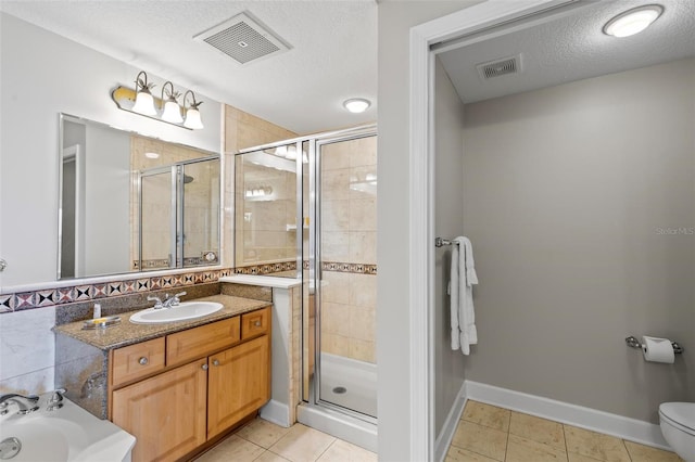 bathroom featuring tile patterned floors, vanity, a shower with door, and a textured ceiling