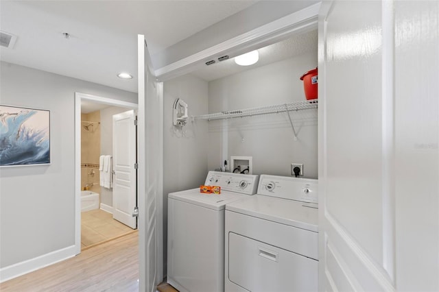 washroom with washing machine and clothes dryer and light wood-type flooring