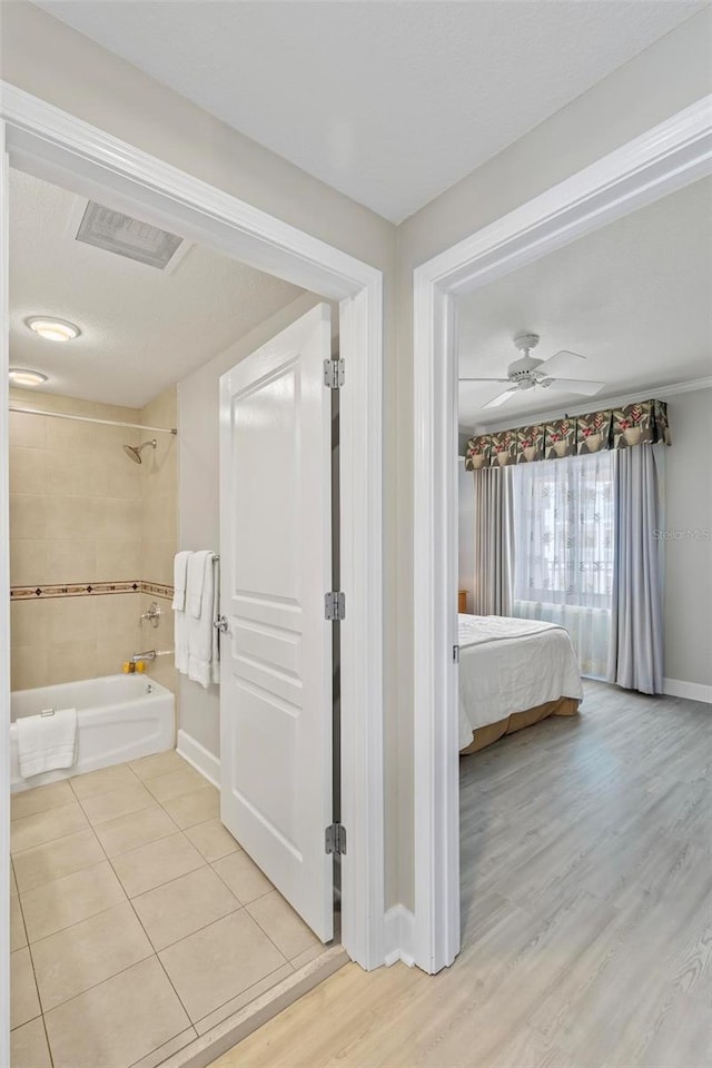 bathroom featuring ceiling fan, hardwood / wood-style floors, and tiled shower / bath combo