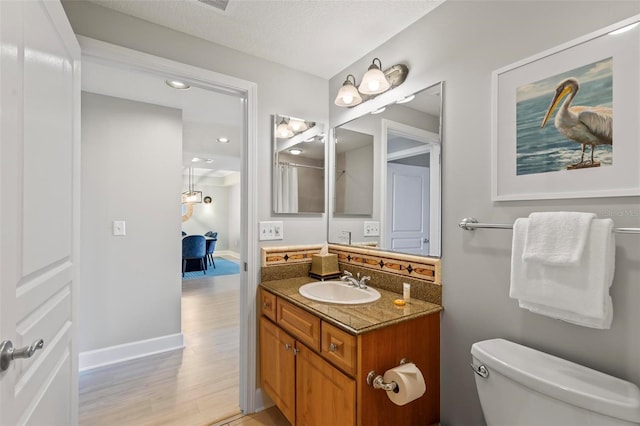 bathroom with vanity, wood-type flooring, a textured ceiling, and toilet