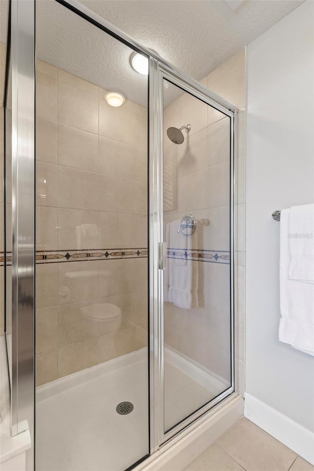 bathroom with tile patterned flooring, a textured ceiling, and walk in shower