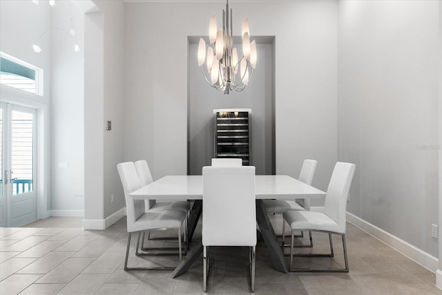 tiled dining room featuring a towering ceiling, an inviting chandelier, and beverage cooler