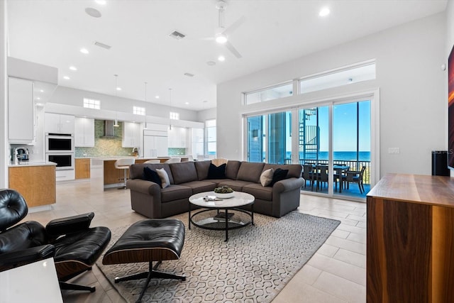 living room with ceiling fan, plenty of natural light, and a water view