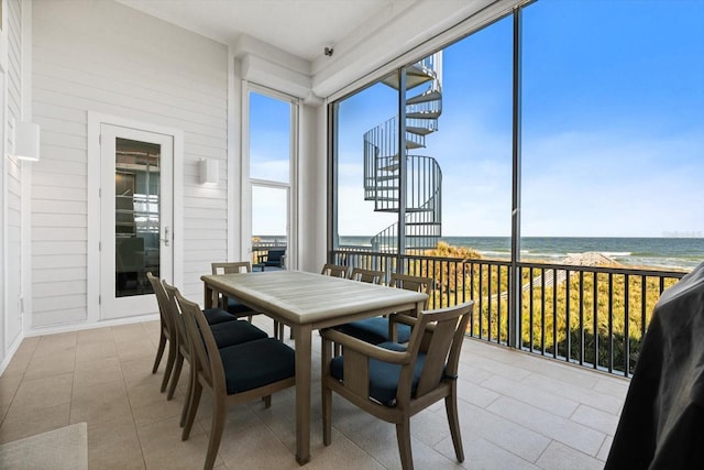 sunroom featuring a view of the beach and a water view