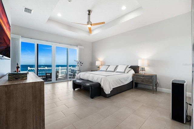 tiled bedroom featuring access to exterior, a water view, a raised ceiling, and ceiling fan