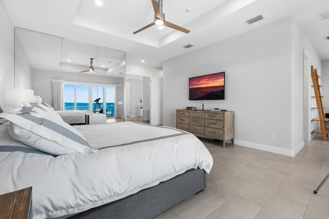 tiled bedroom featuring a raised ceiling and ceiling fan