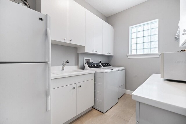 laundry area featuring washing machine and clothes dryer, sink, and cabinets