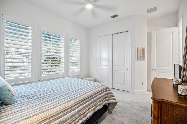 carpeted bedroom featuring multiple windows, ceiling fan, and a closet