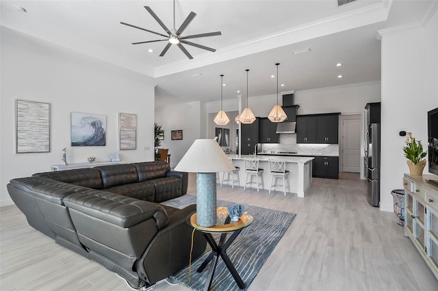 living room with ceiling fan, ornamental molding, and light wood-type flooring