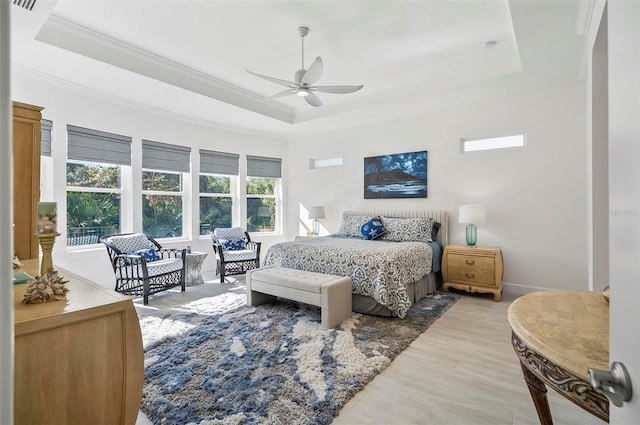 bedroom with crown molding, ceiling fan, a raised ceiling, and light hardwood / wood-style floors