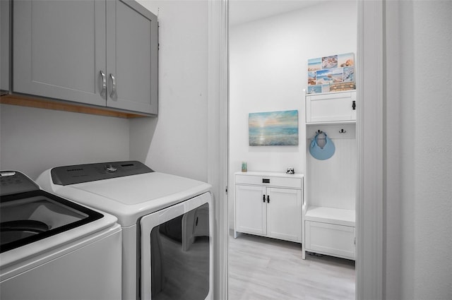 laundry room featuring separate washer and dryer, cabinets, and light wood-type flooring