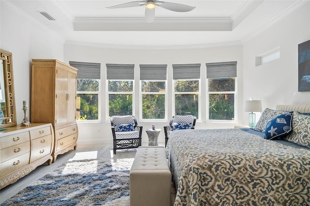 bedroom featuring ceiling fan, ornamental molding, a tray ceiling, and hardwood / wood-style floors