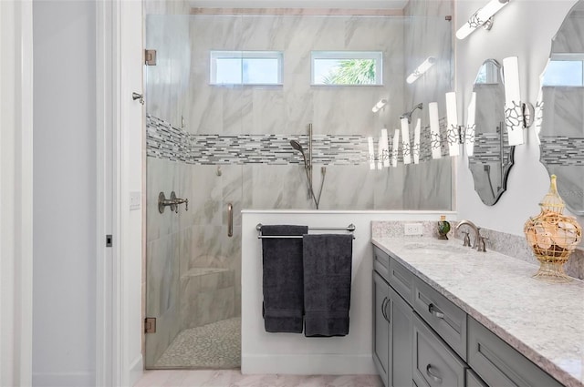 bathroom with vanity, a shower with door, and a wealth of natural light