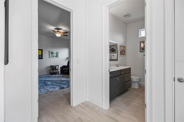 bathroom featuring hardwood / wood-style flooring, ceiling fan, vanity, and toilet