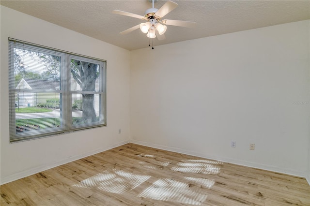 empty room with a textured ceiling, light wood-type flooring, and ceiling fan